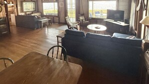 A rustic interior with a wooden ceiling, a bar area, and a seating area with a television. - LARGE RUSTIC COTTAGE. SEBAGO LAKE BEACHFRONT (SEBAGO)