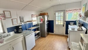 A compact kitchen with white cabinetry, a refrigerator, a stove, and a microwave. - LARGE RUSTIC COTTAGE. SEBAGO LAKE BEACHFRONT (SEBAGO)