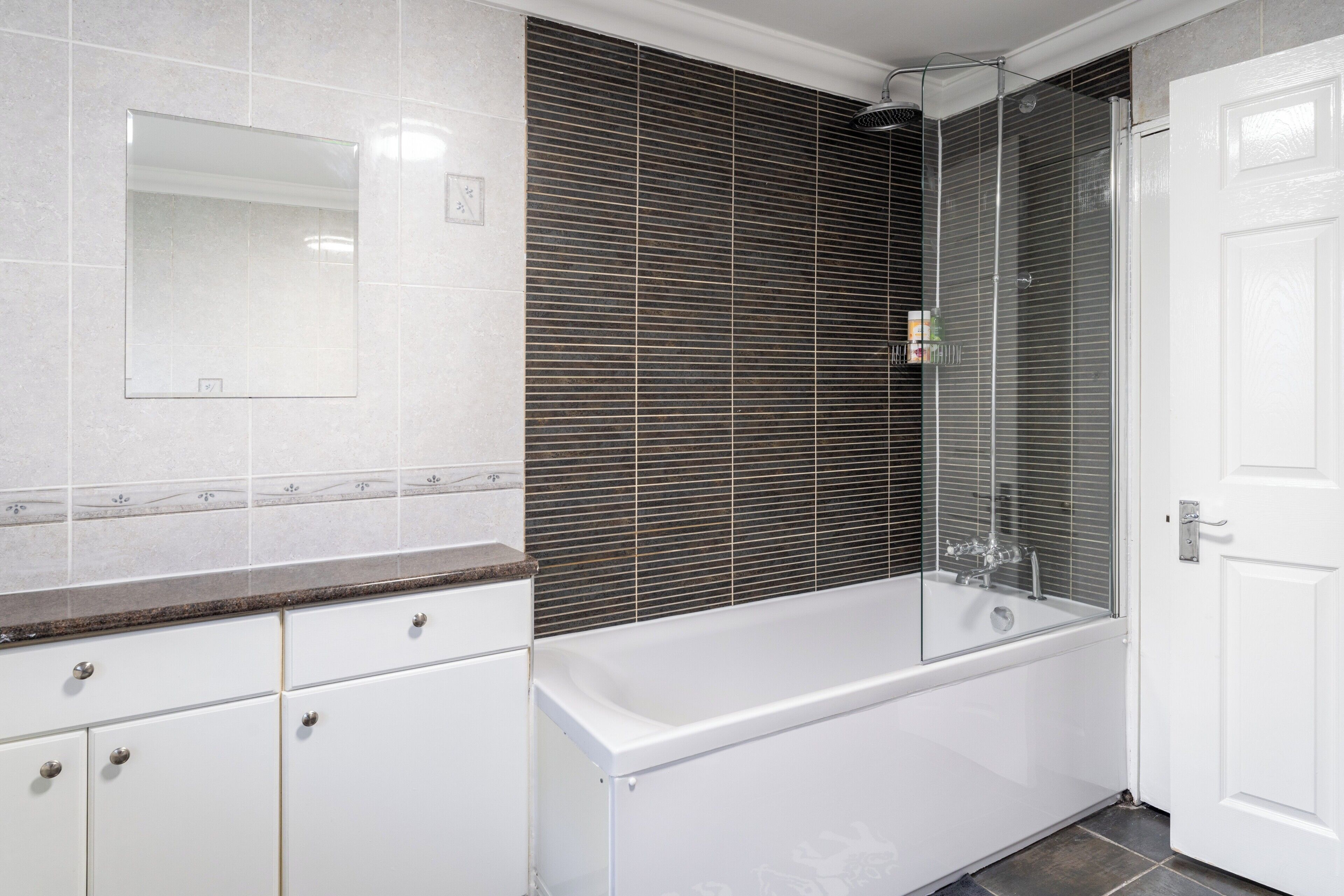 A modern bathroom with a white bathtub, a large mirror, and a shower enclosure.