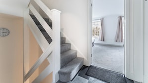 Una escalera con un reloj, una puerta que da a un balcón y vistas al exterior.