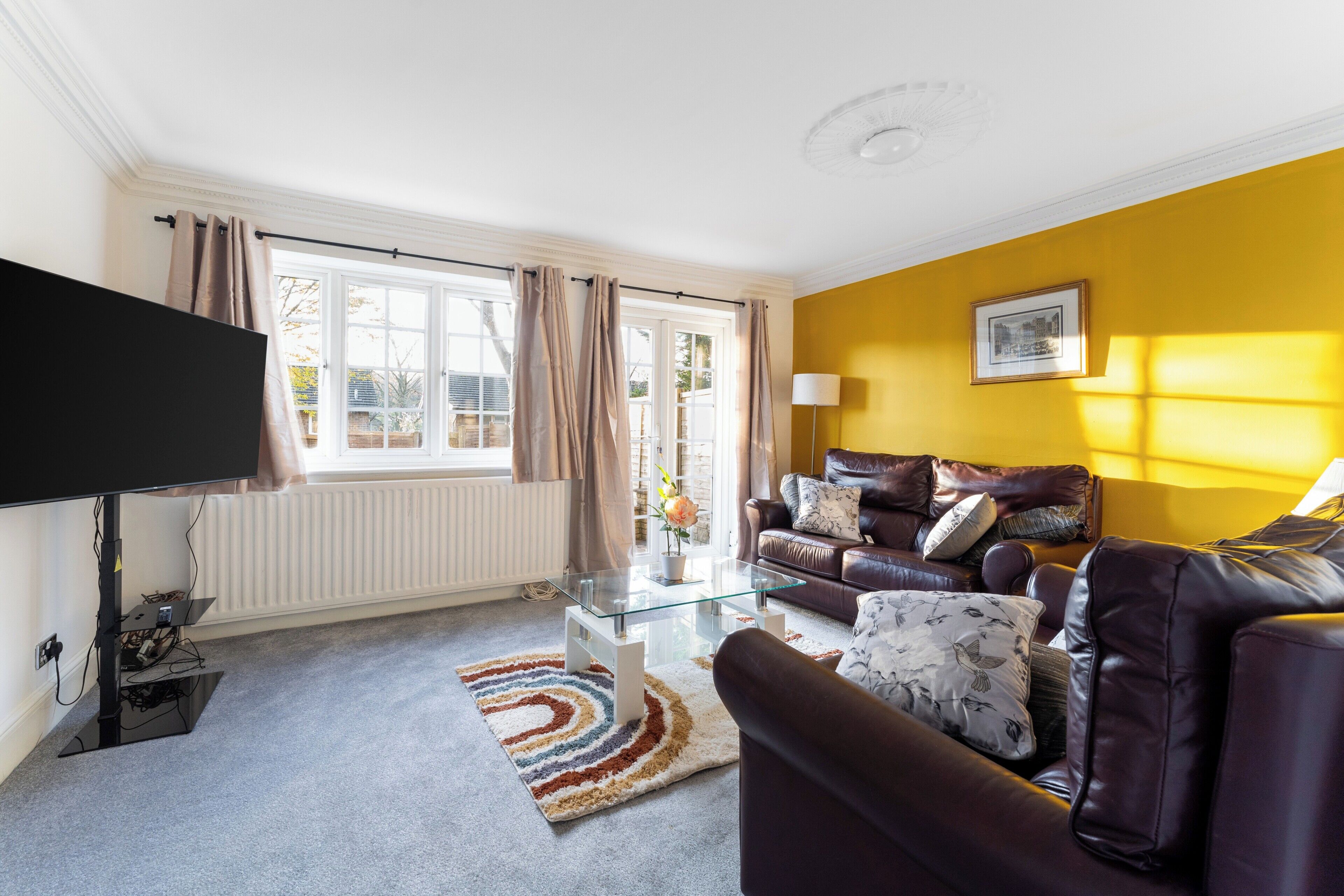A living room with a sofa, a glass coffee table, and a flat-screen TV.