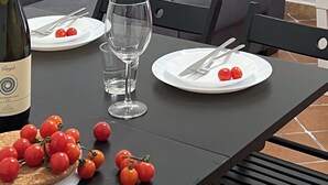 A dining table set with plates, cutlery, a wine bottle, and cherry tomatoes.