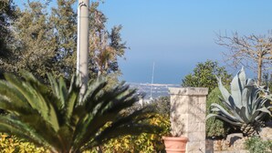 Ein Garten mit einem Steinpfeiler, einem Blumentopf und Blick aufs Meer.