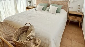 A spacious bedroom with a large bed, two nightstands, a wicker chair, and a hanging light fixture. - Villa Majanicho with pool (Majanicho)