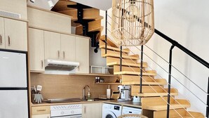 A modern kitchen with a round dining table, wicker chairs, a built-in oven, and a staircase with a wooden railing. - Villa Majanicho with pool (Majanicho)