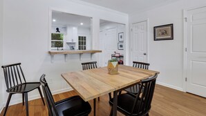 A dining area with a wooden table and black chairs, a kitchen visible through an open doorway, and a framed picture on the wall. - 0.5 mi UGA Stadium & Campus– 2 BR 2.5 BA Athens Townhome with King, Queen + Twin (Athens)