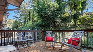 A wooden deck with two rocking chairs and a table, surrounded by a metal railing. - 0.5 mi UGA Stadium & Campus– 2 BR 2.5 BA Athens Townhome with King, Queen + Twin (Athens)