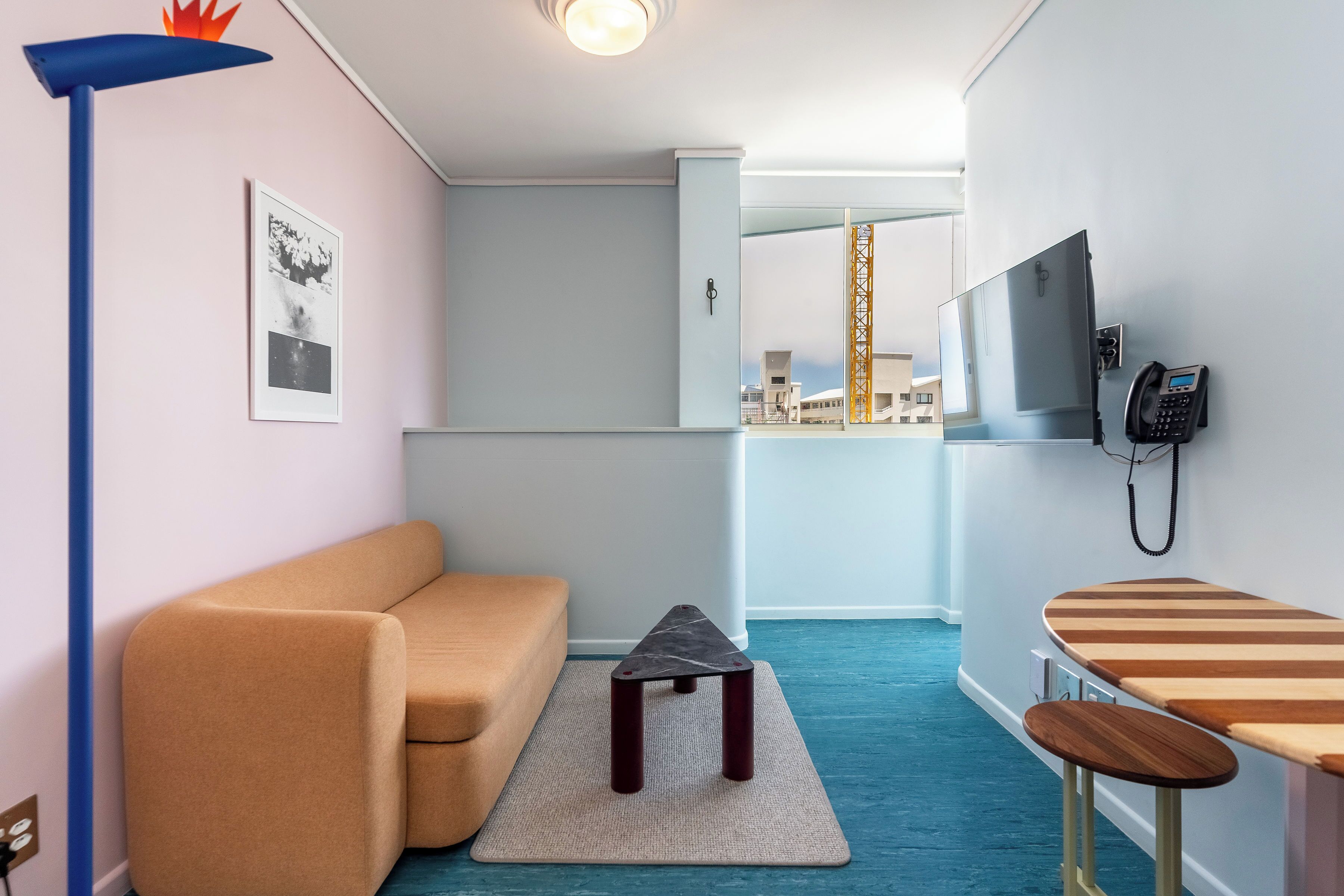 A compact living space with a sofa, a small table, a mirror, and a phone on the wall.