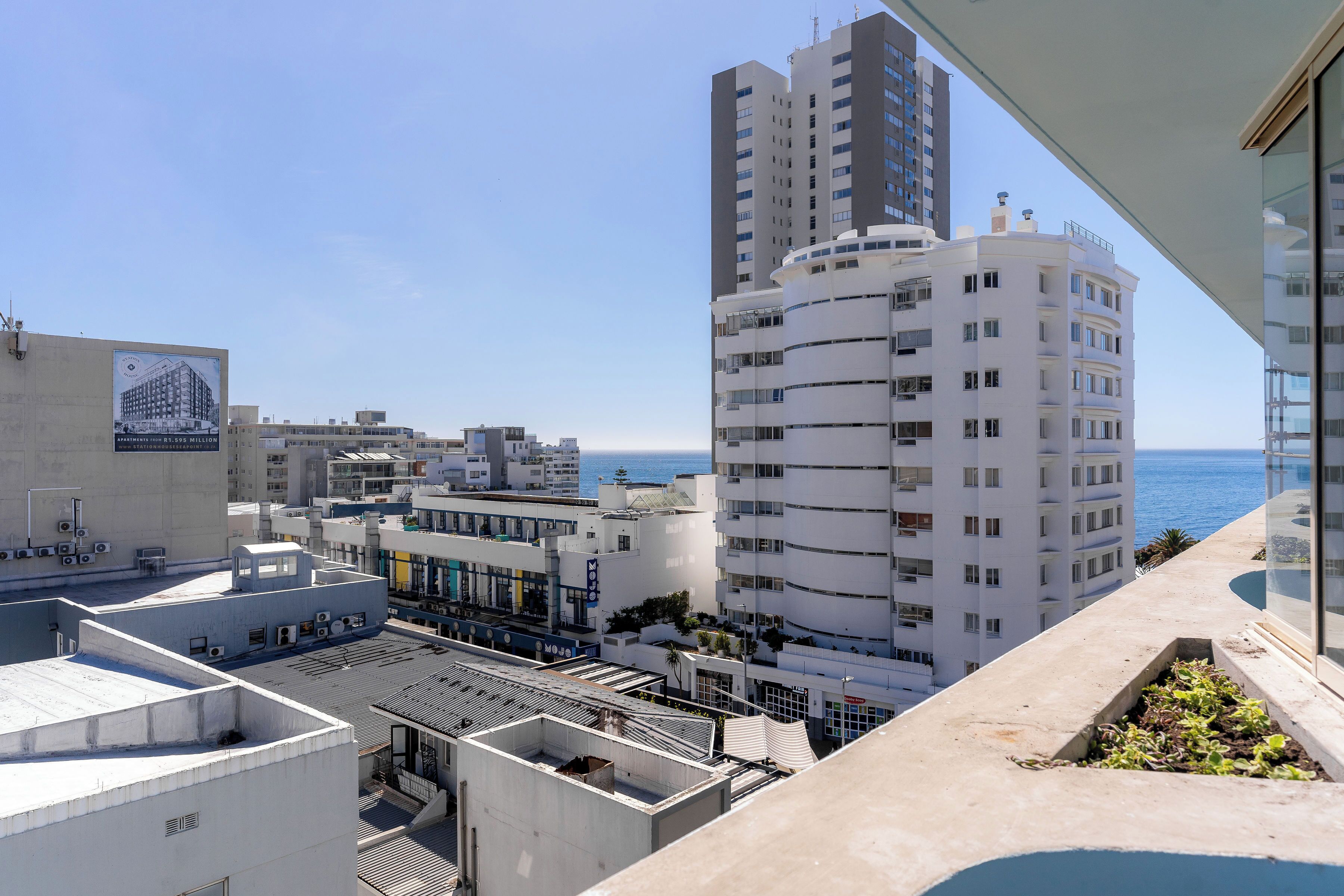 A high-rise building with a view of the sea, featuring multiple balconies and a rooftop terrace.