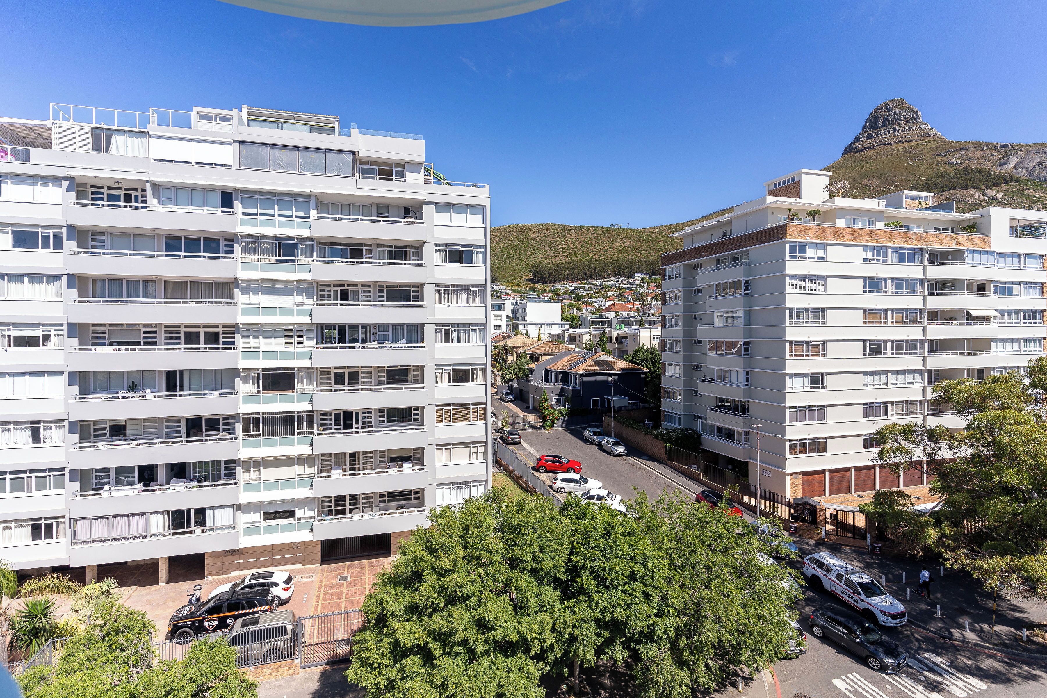A multi-story residential building with balconies and a view of a mountain.