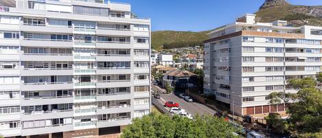 A multi-story residential building with balconies and a view of a mountain.