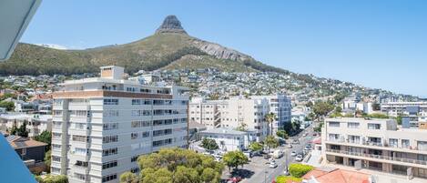 A cityscape with a prominent mountain in the background, modern buildings, and a clear sky.