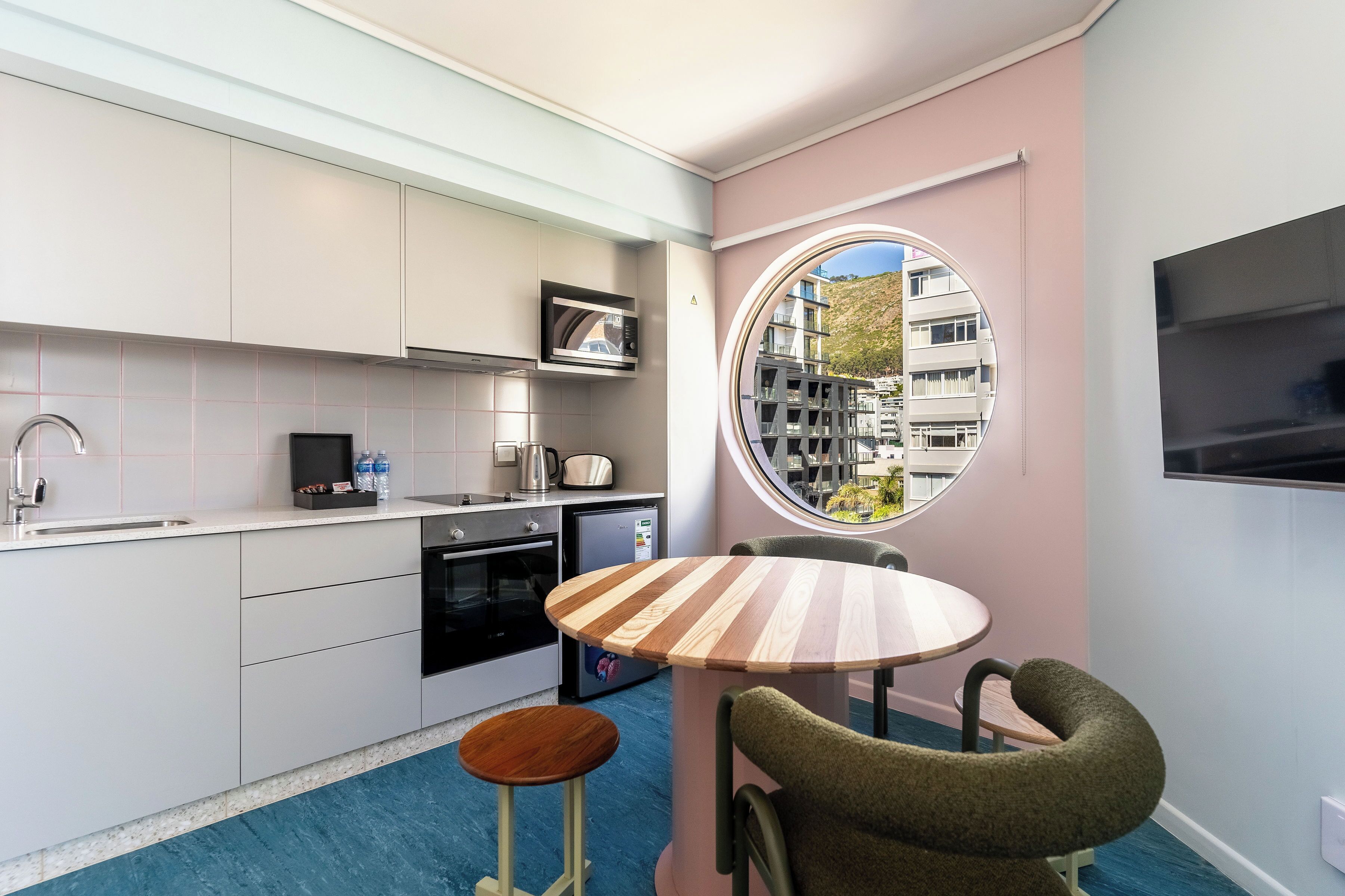 Cocina compacta con electrodomésticos modernos, una mesa redonda para comer y vistas a través de una ventana.