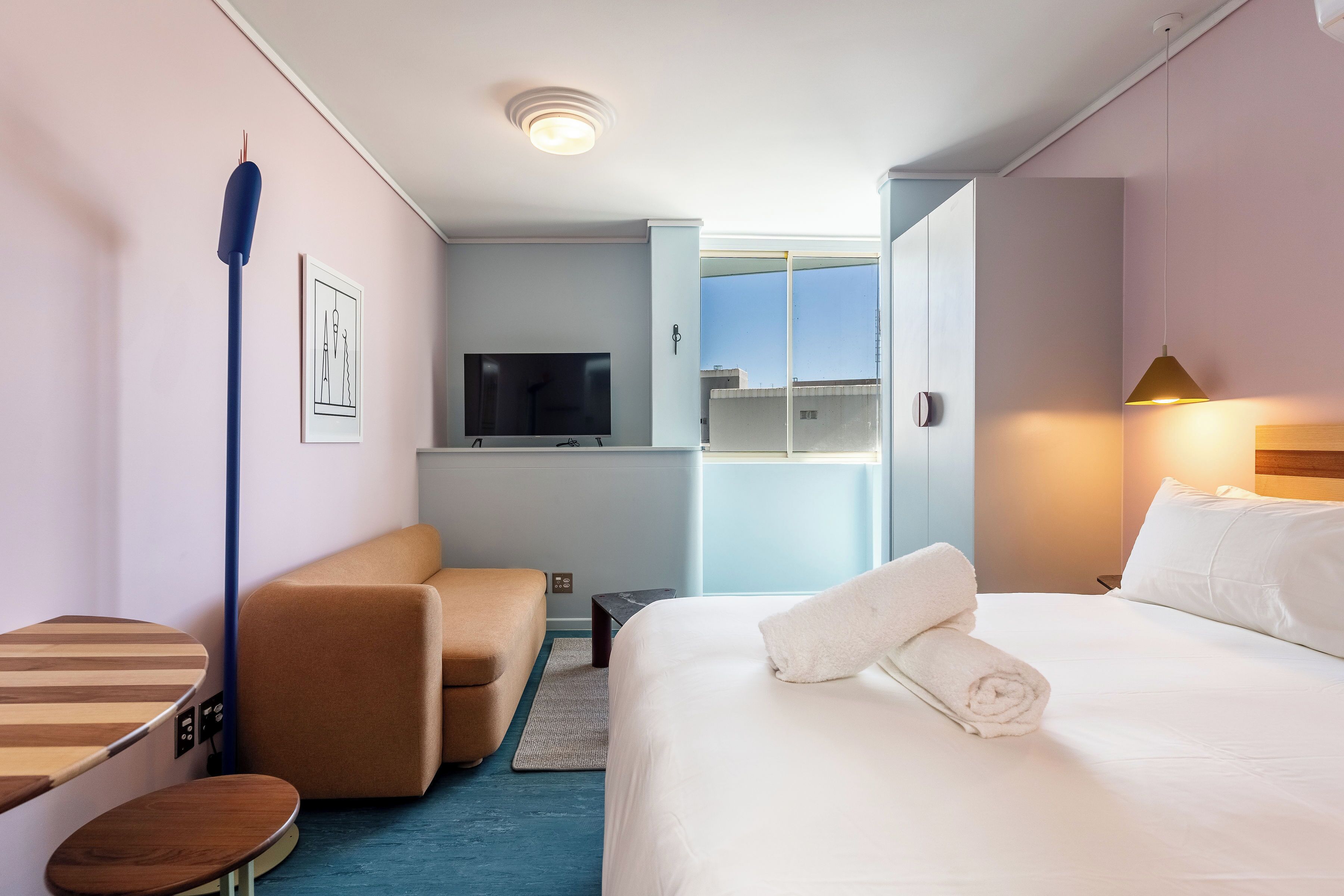 Habitación de hotel con cama, sofá, televisor y ventana con vistas.