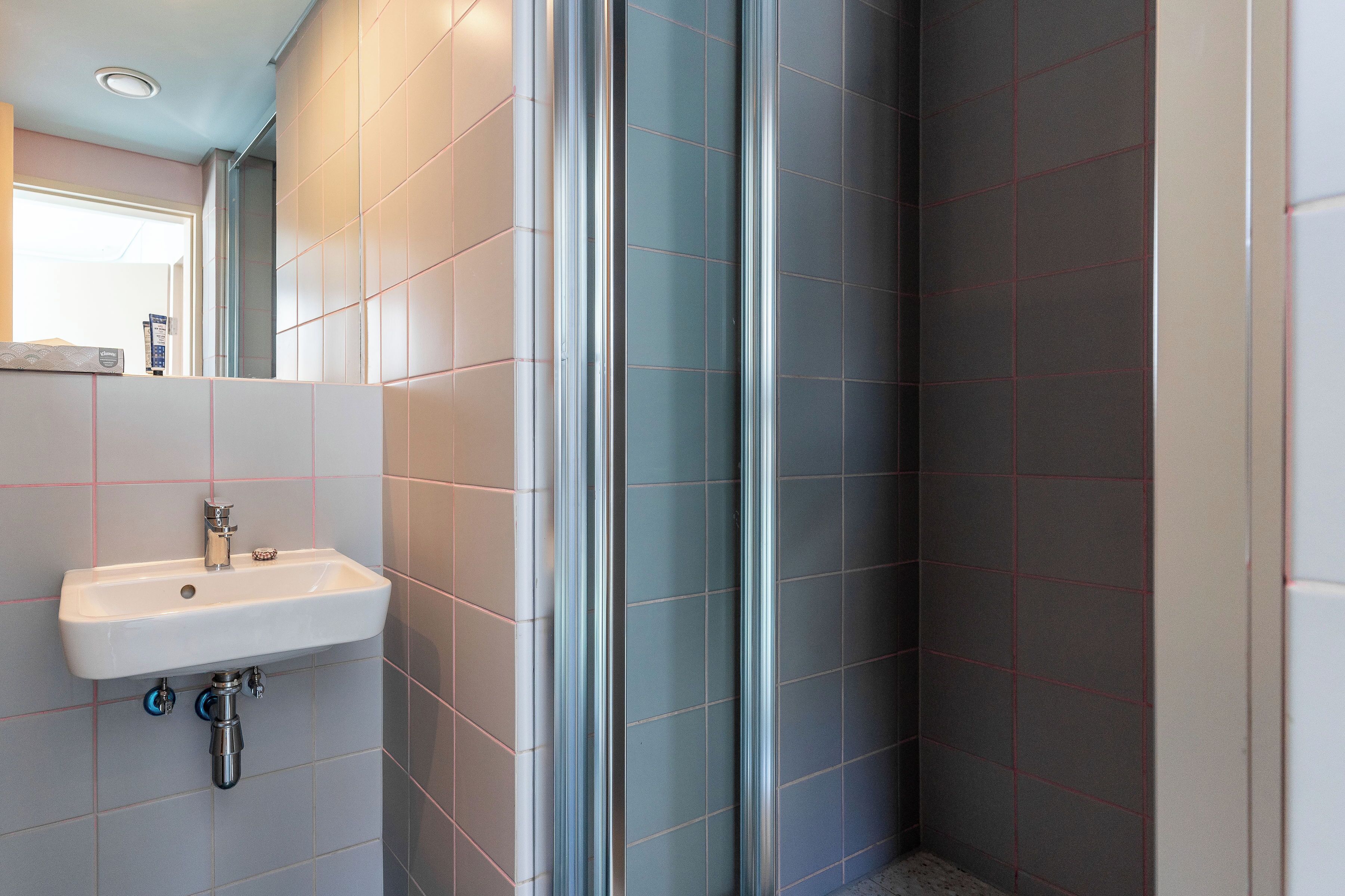 A bathroom with a sink, a mirror, and tiled walls.