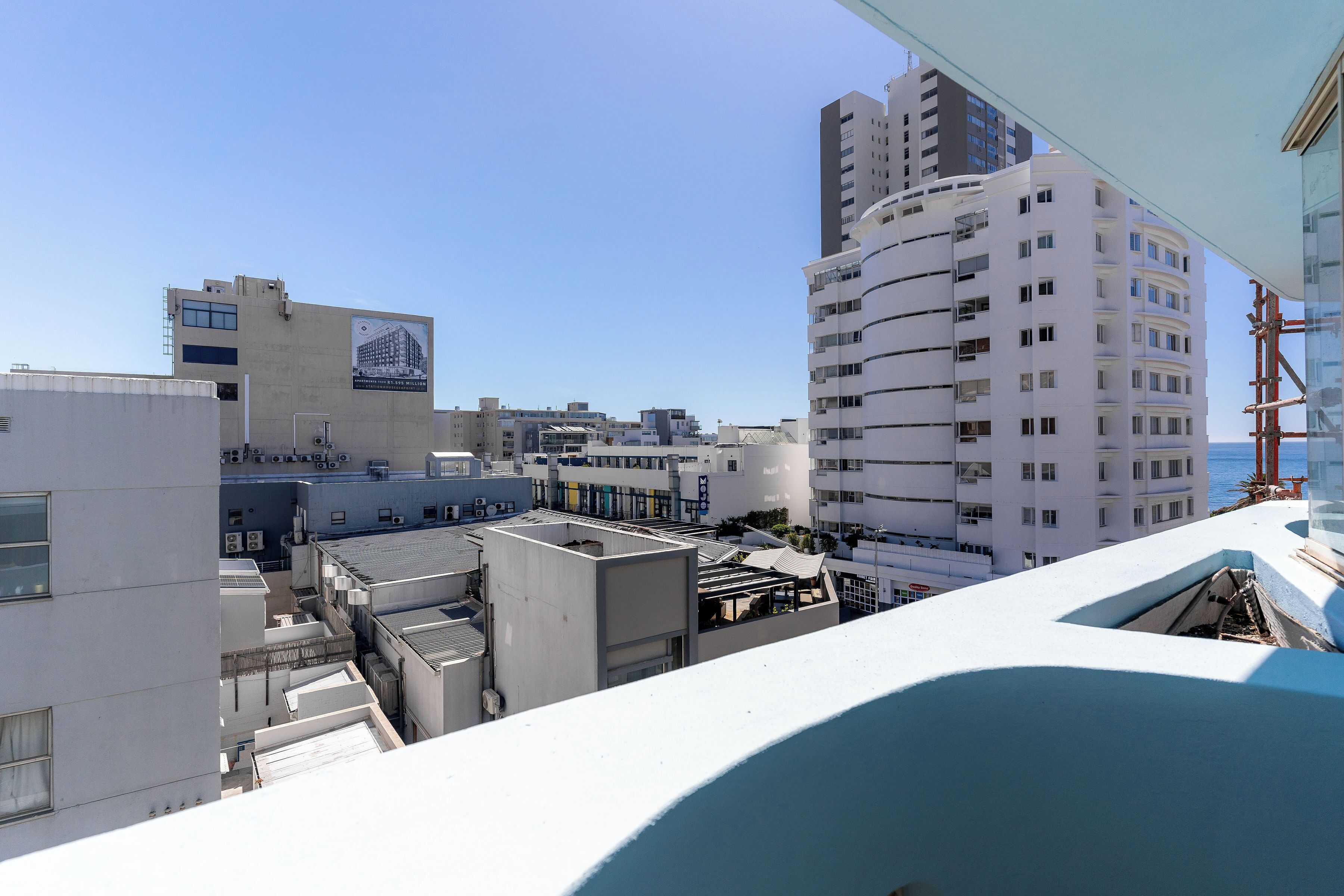 A high-rise building with multiple balconies and a clear view of the sea.