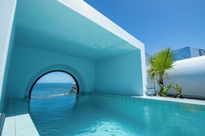 A clear blue pool with a view of the sea, a white building, and a palm tree. - The Tropicana Hotel (Cape Town)