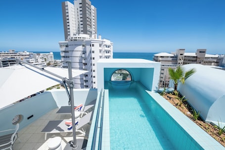 Una piscina al aire libre, sillones reclinables de piscina