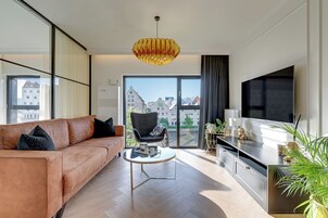 A modern living room with a sofa, armchair, coffee table, and a TV.
