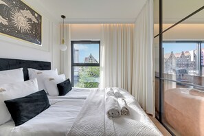 Een hotelkamer met een groot bed, uitzicht op gebouwen en een balkon.