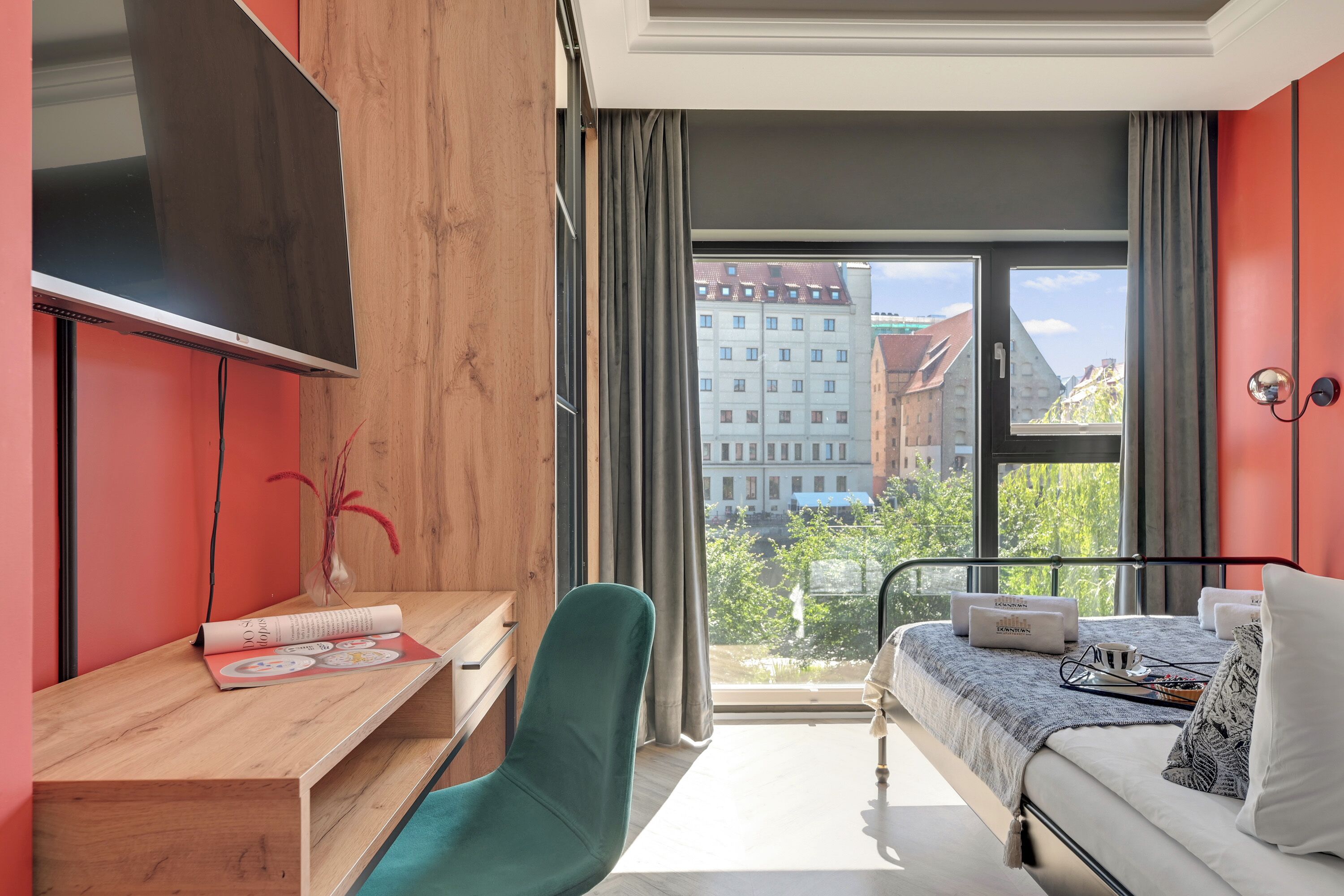 Une chambre d’hôtel moderne dotée d’une grande fenêtre, d’un lit avec vue sur la ville, d’un bureau avec une chaise et d’un téléviseur à écran plat.