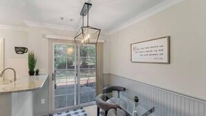 A modern kitchen with a glass door leading to a patio, a pendant light, and a framed quote on the wall. - Golf Oasis Modern Townhome! (Charlotte)