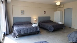 A hotel room with two beds, a wardrobe, a bedside table with a lamp, and a window with curtains. - Palermo Soho G4827 - Modern, Spacious and Luminous Apartments (Buenos Aires)