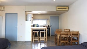 A compact living space with a kitchenette, a dining area with wooden chairs, and a sofa. - Palermo Soho G4827 - Modern, Spacious and Luminous Apartments (Buenos Aires)