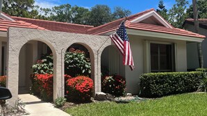 A house with a red-tiled roof, an American flag, and a well-maintained lawn.