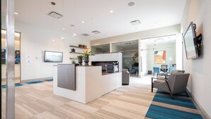 A modern office space with a reception desk, a seating area with a sofa and armchairs, and a glass partition separating the workspace from the lounge area. - 5BR Stay Near Everything Orlando Offers (10382PG) (Orlando)