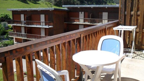 Eine Holzterrasse mit Tisch und Stühlen mit Blick auf eine Berglandschaft.