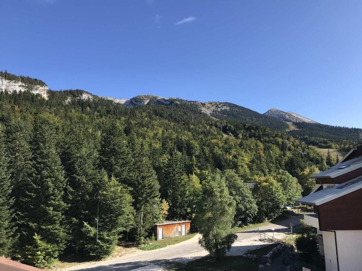 Un paysage montagneux avec de vastes forêts et un petit chalet.