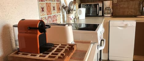 A compact kitchen with a waffle maker on a countertop, a toaster, a coffee maker, and a dishwasher.