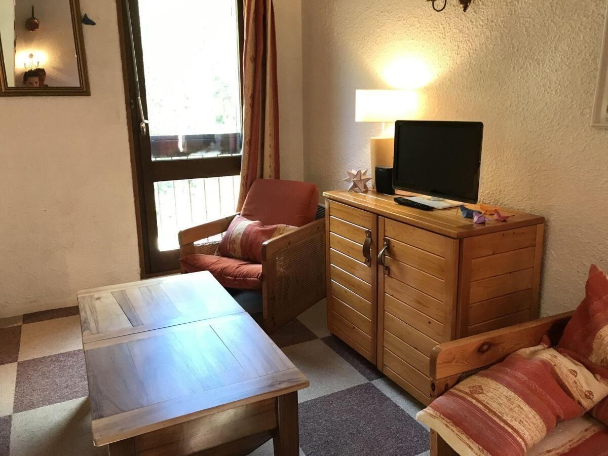 Een kamer met een houten tafel, een bank, een kast en een televisie erboven.