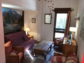 Ein gemütliches Wohnzimmer mit einer Couch, einem Couchtisch und einer TV-Bank mit einem Laptop.