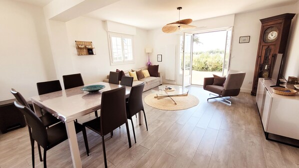 A modern living space with a dining area, sofa, and a large wooden cabinet.