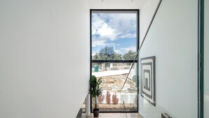 A modern interior with a large glass door leading to an outdoor area, a potted plant, and a framed artwork on the wall. - Hazel Yellow Villa, Sintra, Lisbon (Sintra)