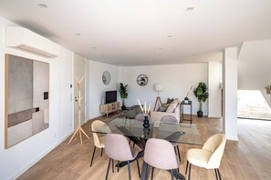 En moderne stue med et glasbord, beige sofaer og et fjernsyn.