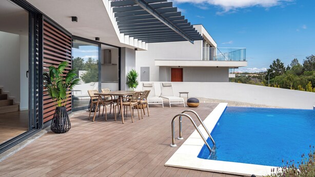 A modern outdoor pool area with a wooden deck, a dining set, and a staircase leading to an upper level. - Hazel Yellow Villa, Sintra, Lisbon (Sintra)