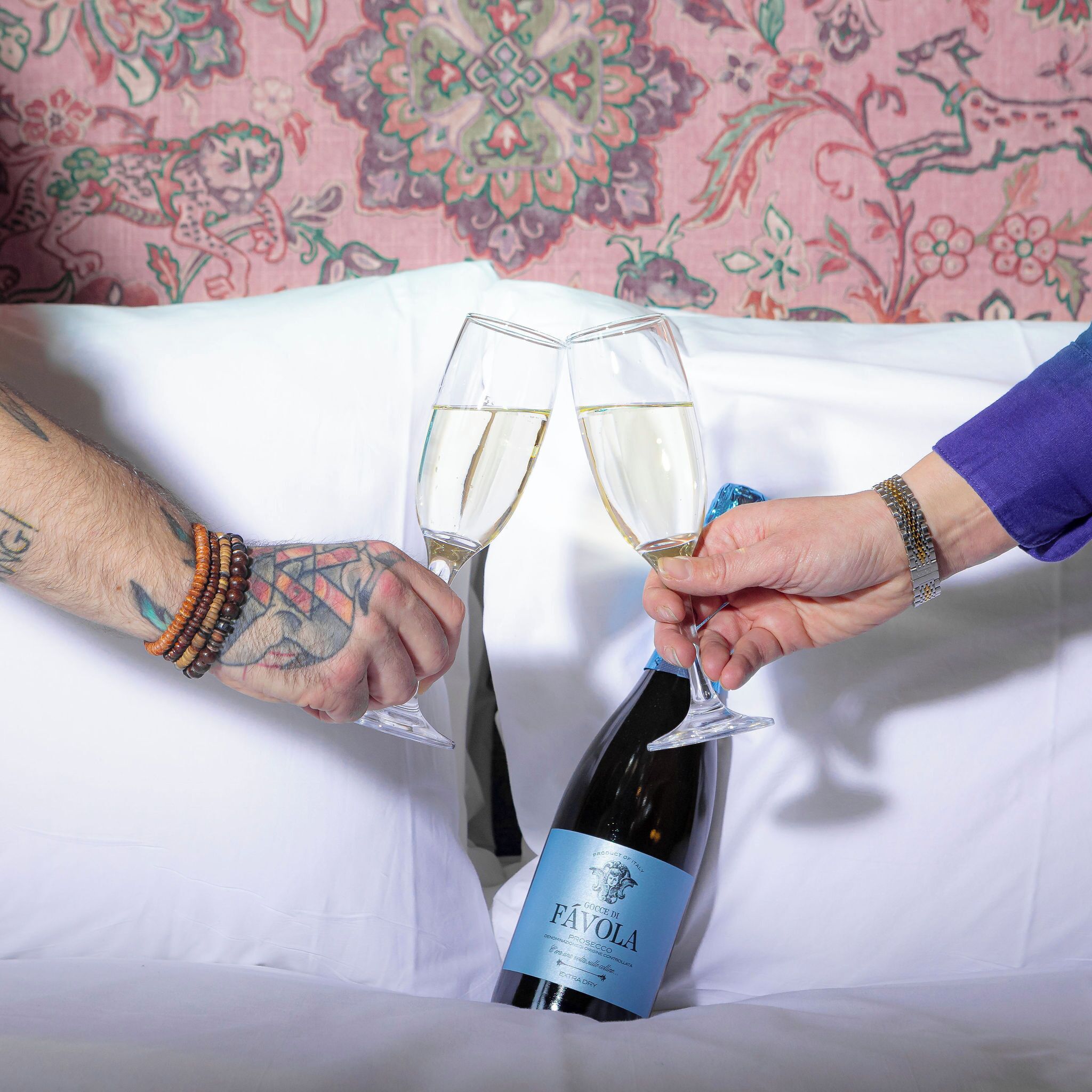Two people toasting with champagne glasses, holding a bottle of FAVOLA wine.