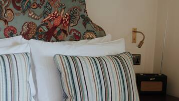 A bed with striped pillows, a patterned headboard, a hanging light, and a radio on a bedside table.