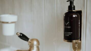 Un lavabo de salle de bain avec un robinet doré et un distributeur de savon noir fixé au mur.