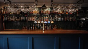 A bar area with multiple liquor bottles, a selection of glasses, and a bar counter. - The Boars Head (Cupar)