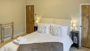 Un lit bien fait, avec une couverture grise, des oreillers blancs et une porte en bois en arrière-plan.