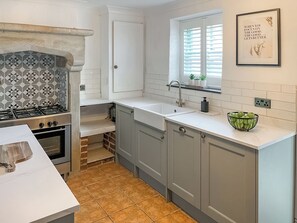 A kitchen with a gas stove, oven, sink, and a window with blinds. - 2 bedroom accommodation in Barnard Castle (Barnard Castle)