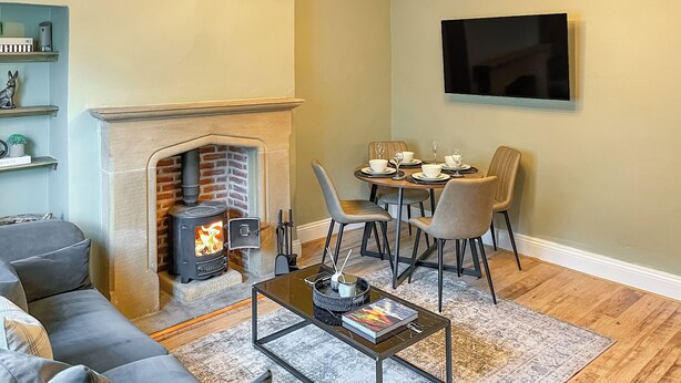 Un salon avec une cheminée, un canapé, une table basse et un coin repas avec des chaises et une table mise pour le repas.