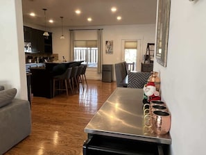 Une cuisine moderne avec un coin repas, un plancher en bois et un bar équipé de verres en cuivre.