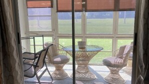 A sliding glass door leading to an outdoor patio with wicker furniture and a view of a grassy area. - Charming 2-bedroom condo in serene Lake Suzy with WiFi, AC (Lake Suzy)