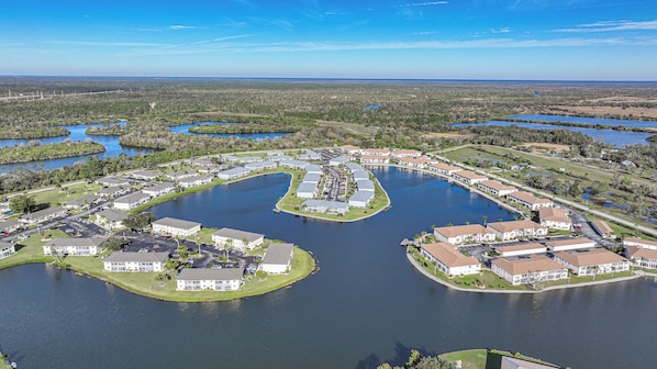 A residential area with houses arranged around a central lake, connected by walkways.