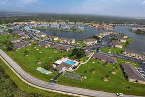 An aerial view of a residential community with multiple buildings, roads, and a lake.